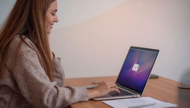 Woman typing email on laptop at work desk
