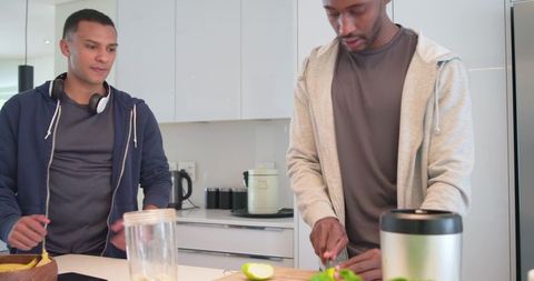 Young diverse men chopping green apple together on bright minimal kitchen countertop