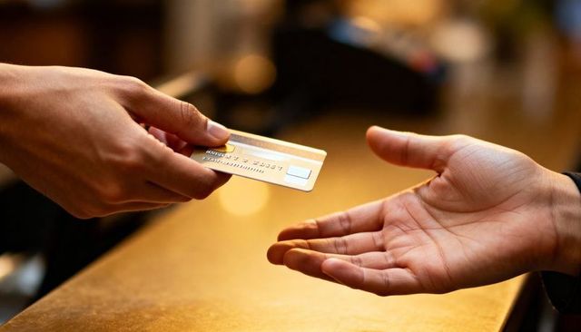Exchanging gold credit card over wooden counter with emv chip closeup retail payment