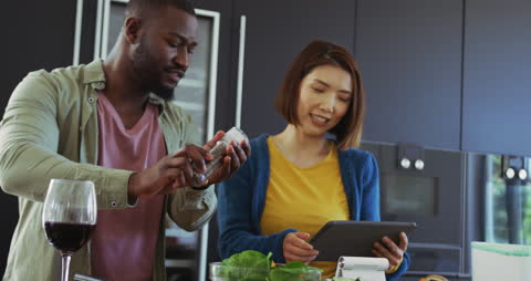 Diverse Couple Cooking Together Using Tablet in Modern Kitchen