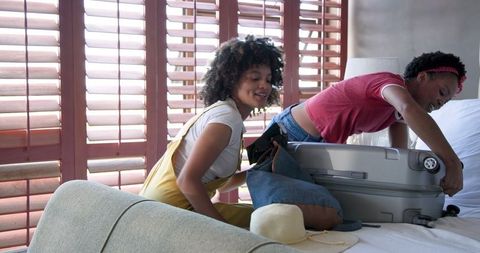 Diverse couple packing suitcase fun vacation preparation