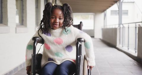 Joyful Girl in Wheelchair Rolling Down Urban Hallway