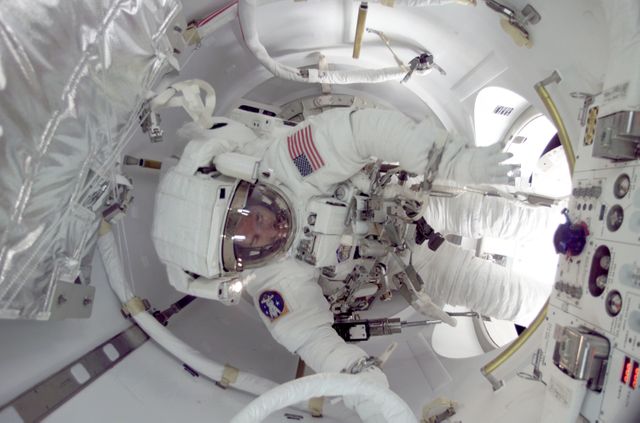 Astronaut participating in extravehicular activity (EVA) during the STS-104 mission, utilizing the newly installed Quest Airlock on the ISS. This image is historic as it demonstrates the utilization of an airlock designed for both American and Russian spacesuits. Ideal for educational articles, space exploration blogs, historical documentation, or coverage of NASA missions.