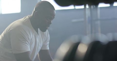 African American Man Resting Between Sets in Gym, Intense Backlit Workout Moment