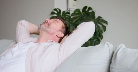 Senior Man Relaxing on Sofa in Minimalist Living Room