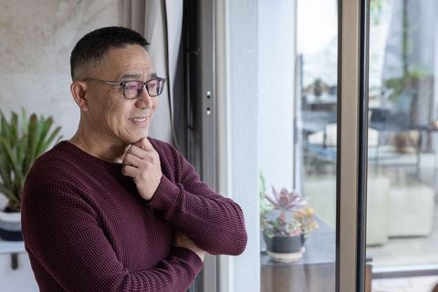 Senior Asian Man Embracing Peaceful Moment by Home window