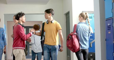 Teenagers socializing in high school hallway