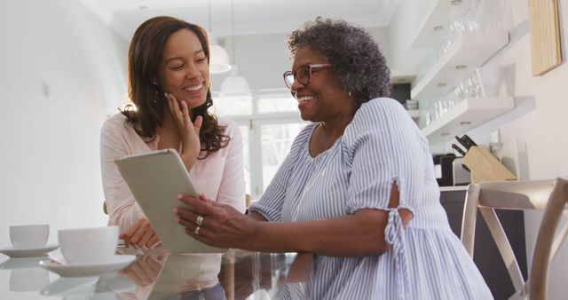 Elderly Woman and Young Adult Using Digital Tablet in Modern Kitchen - Download Free Stock Images Pikwizard.com