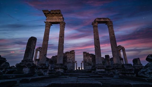 Framing ancient temple at twilight with towering fluted columns and violet sunset sky