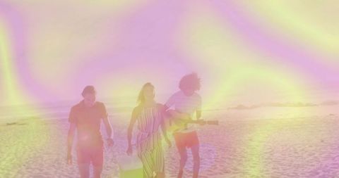 Friends walking on pastel sunset beach carrying tote bag and playing guitar