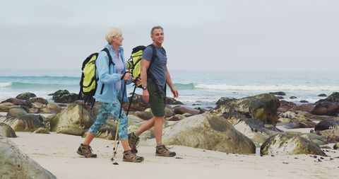 Senior Couple Hiking with Poles Along Rocky Beachfront