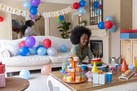 Couple decorating living room for colorful birthday party with cake and cupcakes