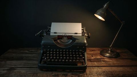 Vintage typewriter on wooden desk with desk lamp in moody atmosphere