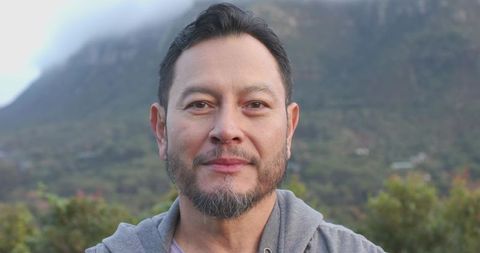 Calm asian man in grey hoodie on misty mountain hike