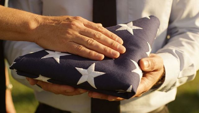 Hands holding folded american flag during military honor presentation close-up