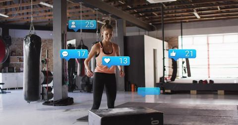 Female athlete training on plyo box in industrial gym with social media engagement icons
