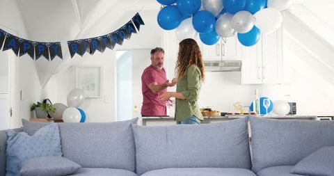 Couple tidying birthday decorations in modern living room