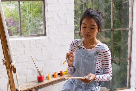 Teenage asian artist in studio contemplating on painting