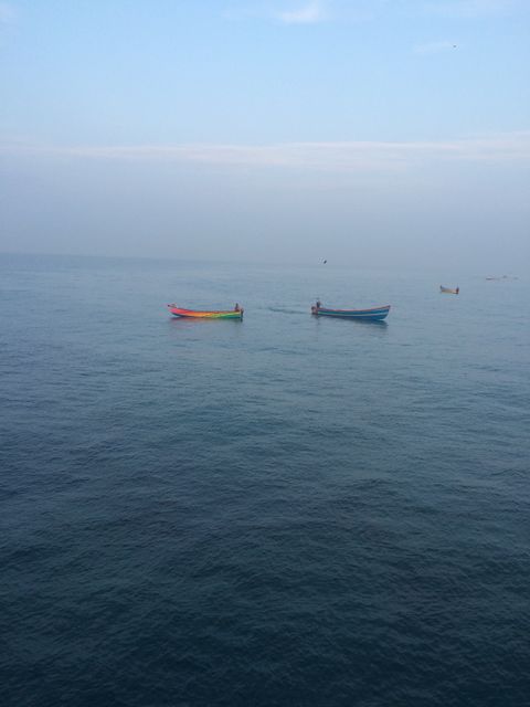 Fishermen in colourful wooden boats floating on calm sea - Download Free Stock Photos Pikwizard.com