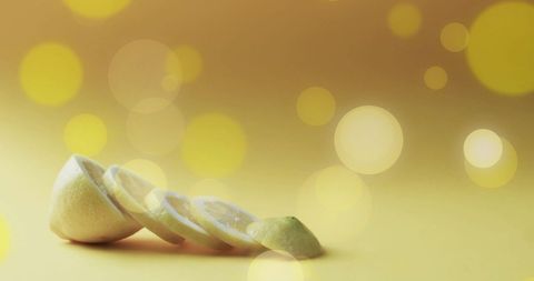 Sliced lemon pieces on soft yellow bokeh background
