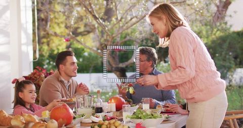 Multigenerational Family Sharing Cozy Fall Meal on Garden Patio, Woman Serving Dish