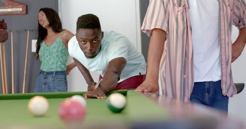 Young Man Focusing on Pool Shot at Friendly Gathering