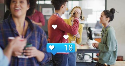 Young professionals sharing laugh and social media likes in open-plan coworking office