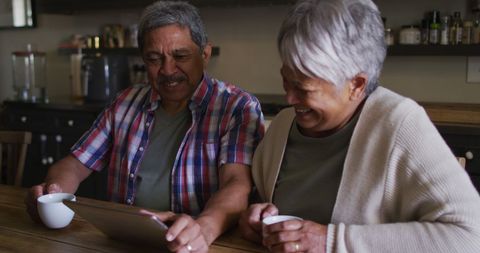 Joyful Senior Couple Using Tablet at Home for Relaxation