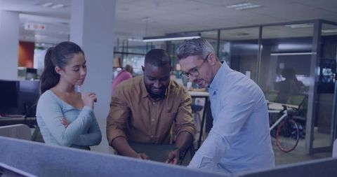 Diverse team collaborating around monitor in modern open-plan office