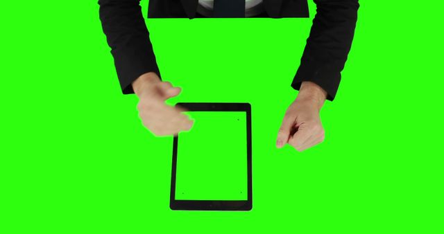 Businessman wearing suit presenting a tablet with a green screen display, useful for digital presentations, advertisements, or business proposals. Perfect for editing and adding custom content or graphics to the tablet screen.