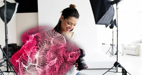 Creative female photographer analyzing dslr with digital overlay