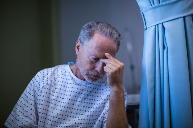 Sad patient sitting on chair with hand on head at hospital