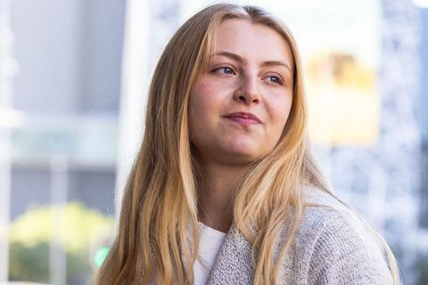 Contemplative blonde woman gazing right in urban plaza wearing light gray cardigan