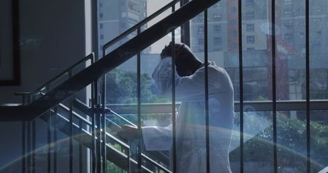 Stressed medical professional leaning on stair railing, pressing forehead, contemplative