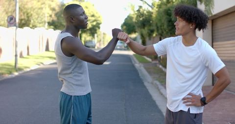 Diverse Male Friends Fist Bump in Sportswear Promoting Friendship