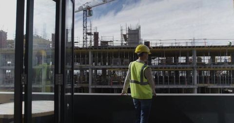 Construction worker overlooking building site with scaffolding