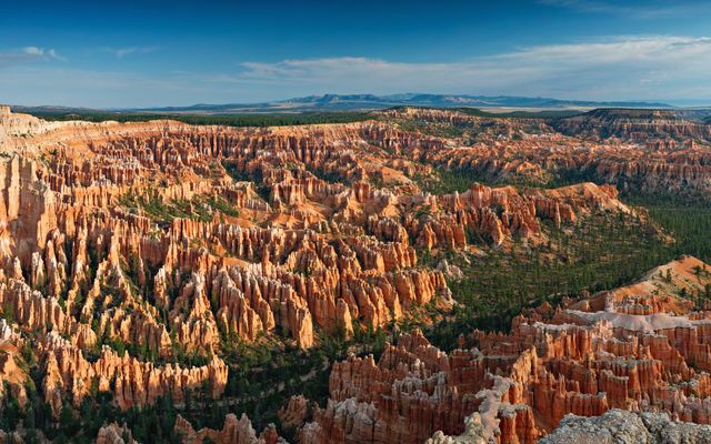 Panoramic view of Bryce Canyon's iconic hoodoos illuminated by the golden light of sunrise, showcasing the stunning natural beauty and unique rock formations of this famous Utah national park. This image can be used for travel websites, brochures, nature wallpapers, or educational materials about geology and national parks.