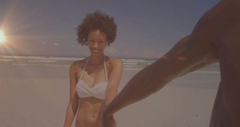 Couple Enjoying Sunshine on Beach Holding Hands