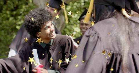 Smiling graduate receiving diploma in cap and gown with golden star confetti outdoors