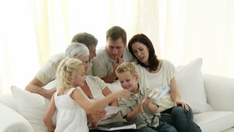 Happy Multigenerational Family Enjoying Photo Album at Home
