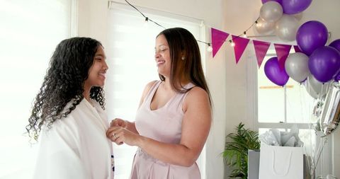 Mother and daughter smiling during celebration with balloons and gifts
