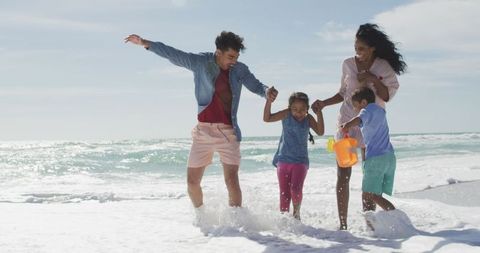 Joyful Family Playing Together on Sunny Beach Shore