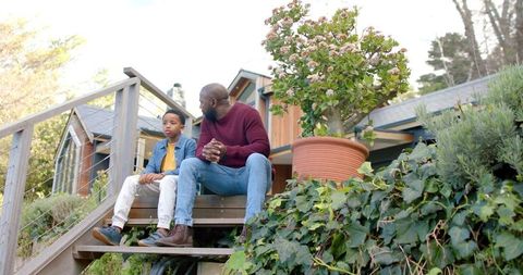 African american father and son sitting on porch steps sharing quiet moment