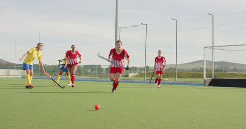 Female Field Hockey Athletes Competing on Outdoor Turf