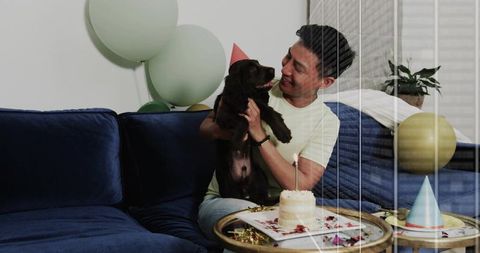 Man holding chocolate labrador puppy celebrating birthday on blue velvet sofa