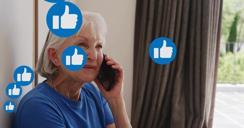 Senior woman talking on smartphone with floating like icons showing social media approval