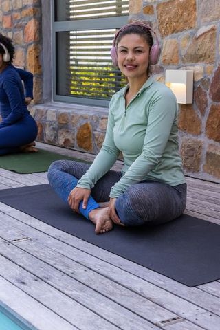 Sunlit poolside yoga session with diverse women wearing headphones on mats for mindfulness