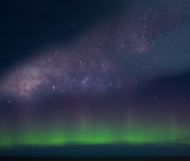 Milky Way galaxy stretching across night sky with visible aurora lights near horizon. Ideal for use in projects related to space exploration, astronomy blogs, nature documentaries, astrophotography, or inspirational backgrounds.
