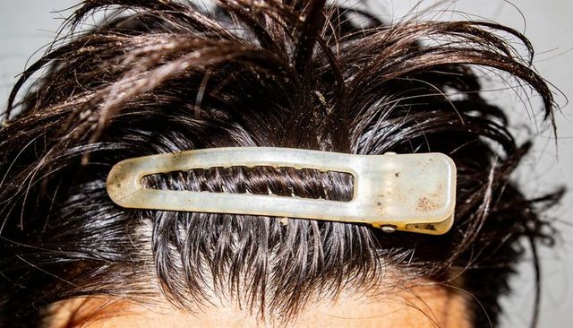 Closeup damp dark hair pulled back with weathered metal barrette on crown for styling