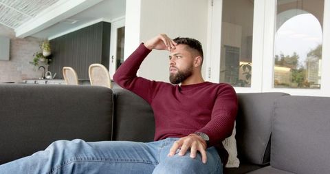 Pensive Bearded Man Leaning on Sofa in Modern Home